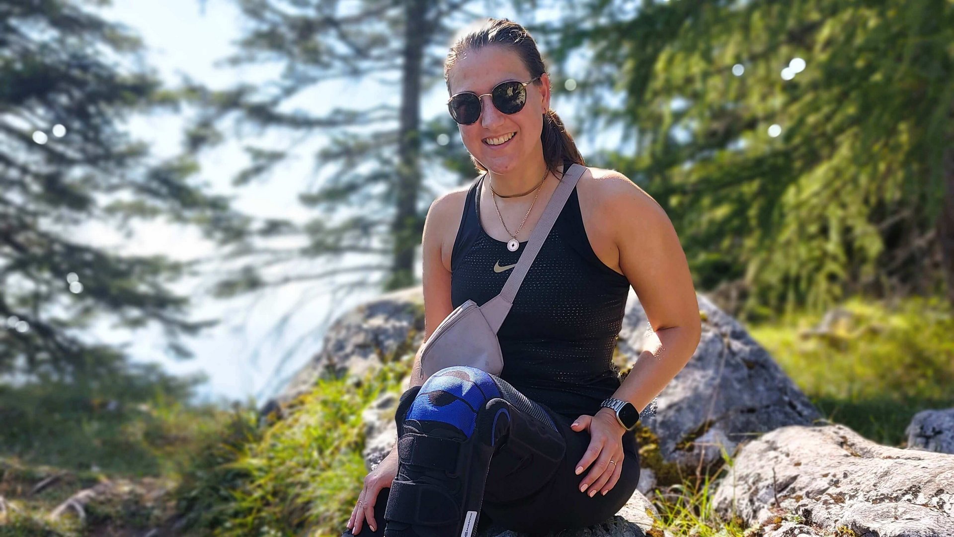 Das Bild zeigt Kniepatientin Katrin mit ihrer Bauerfeind-Orthese SofTec Genu im Wald bei einer Wanderpause.